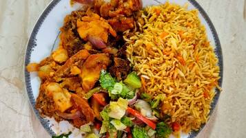 Un plato de comida con arroz, verduras y carne.