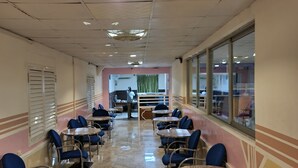 A long corridor with tables and chairs, a person in the distance, and a window on the right. - Hotel Rayan Djibouti (Djibouti)