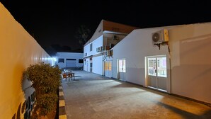 A narrow corridor with a tiled floor, a white wall with a window, and an air conditioning unit mounted on the wall. - Hotel Rayan Djibouti (Djibouti)