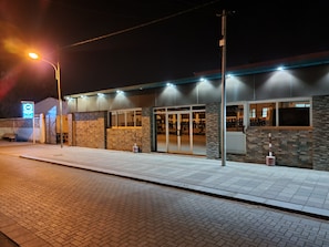 A building with a brick facade, large glass doors, and a sign indicating a business or service area.