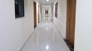 A long, narrow hallway with white walls and a shiny floor, leading to a door marked with the number 106. - Hotel Rayan Djibouti (Djibouti)