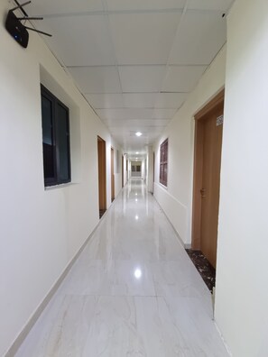 A long, narrow hallway with white walls and a shiny floor, leading to a door marked with the number 106. - Hotel Rayan Djibouti (Djibouti)