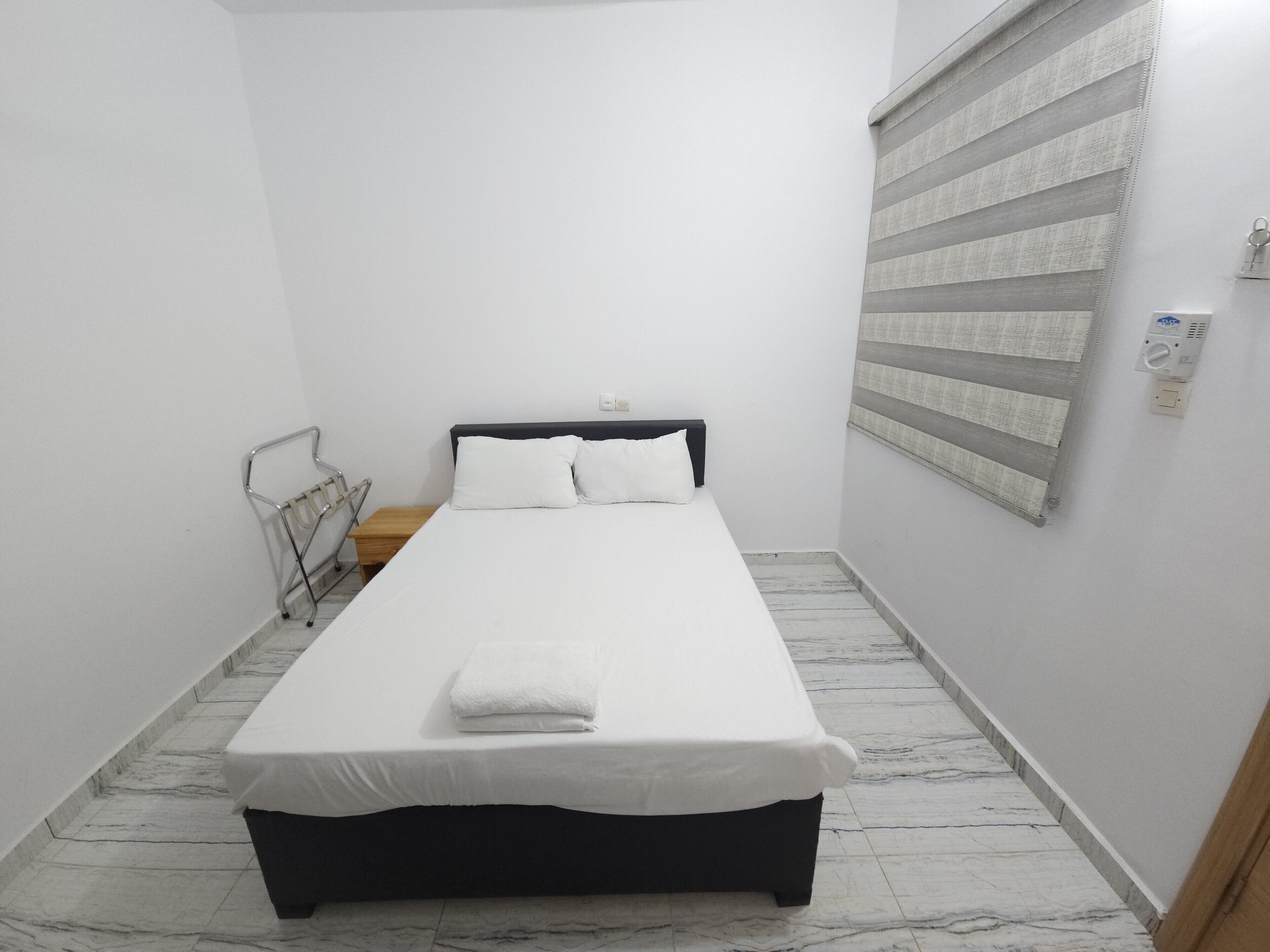 Un dormitorio pequeño y ordenado con una cama individual, una mesita de noche y un radiador.