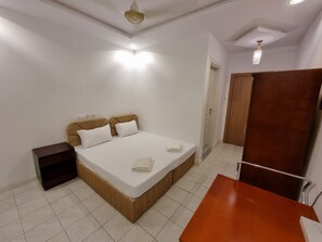 Un dormitorio con cama, mesita de noche y un armario de madera.