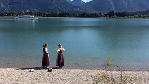 A lake with mountains in the background and a boat on the water. - Spacious, inviting apartment near Füssen  close Neuschwanstein castle (Hopferau)