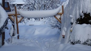A snow-covered outdoor area with a wooden structure, possibly a deck or porch, surrounded by snow-laden trees. - Spacious, inviting apartment near Füssen  close Neuschwanstein castle (Hopferau)