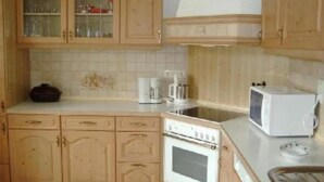 A kitchen with wooden cabinets, a microwave, an oven, and a coffee maker. - Spacious, inviting apartment near Füssen  close Neuschwanstein castle (Hopferau)