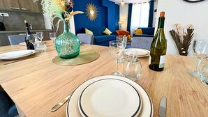 Un comedor con una mesa de madera dispuesta para una comida, un jarrón decorativo y una botella de vino.