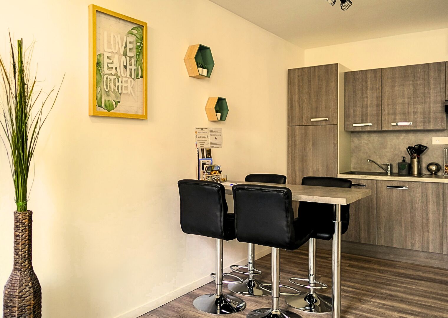 Uma cozinha moderna com área de refeições, com banquetas e uma frase motivacional emoldurada na parede.