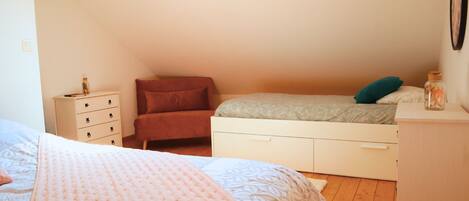 Un dormitorio con cama en literas, un aparador, una mesita y un estante en la pared.