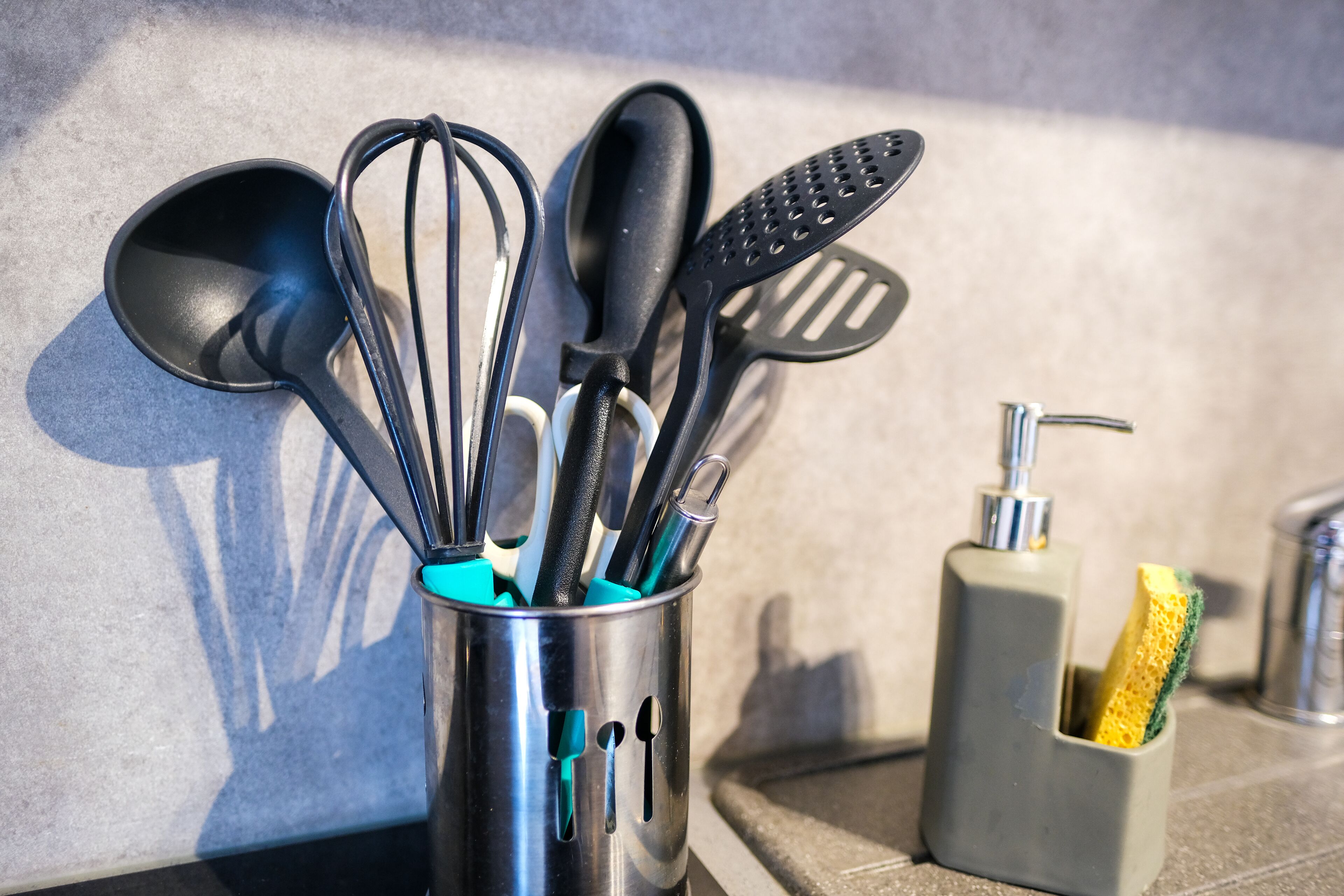 Un organizador de utensilios de cocina con diversos utensilios y una esponja.
