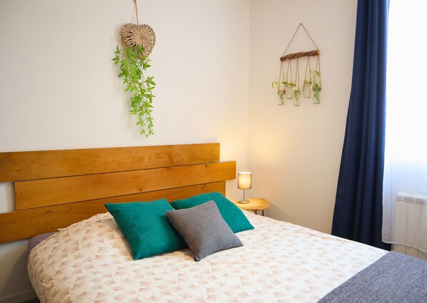 Una cama con cabecera de madera, dos almohadas y una colcha estampada.
