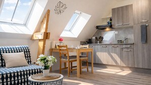 Un apartamento moderno con techo estilo loft, comedor, cocina y sala de estar con sofá y mesa de centro.