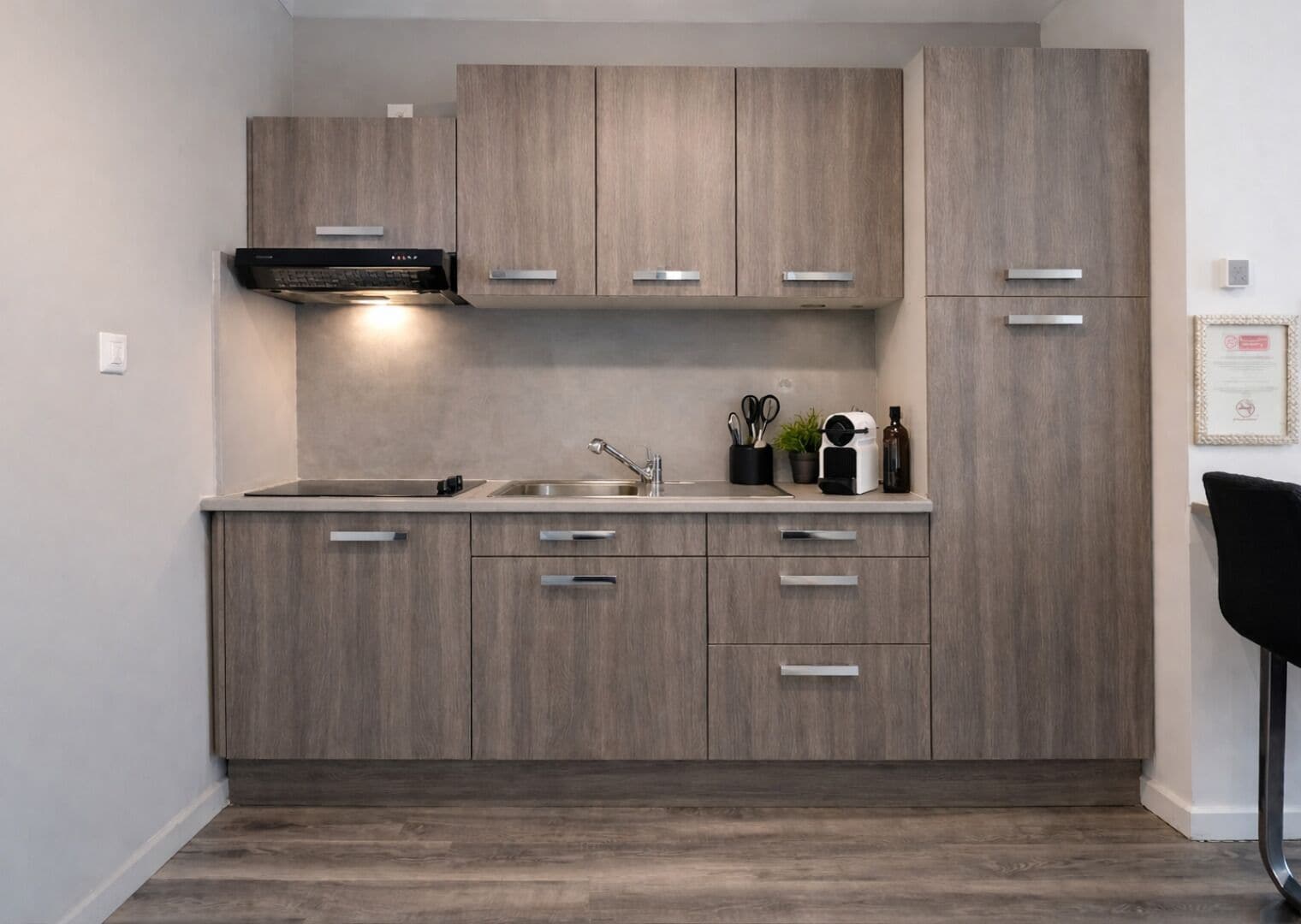 A modern kitchen with wooden cabinets, a built-in oven, and a stainless steel sink.