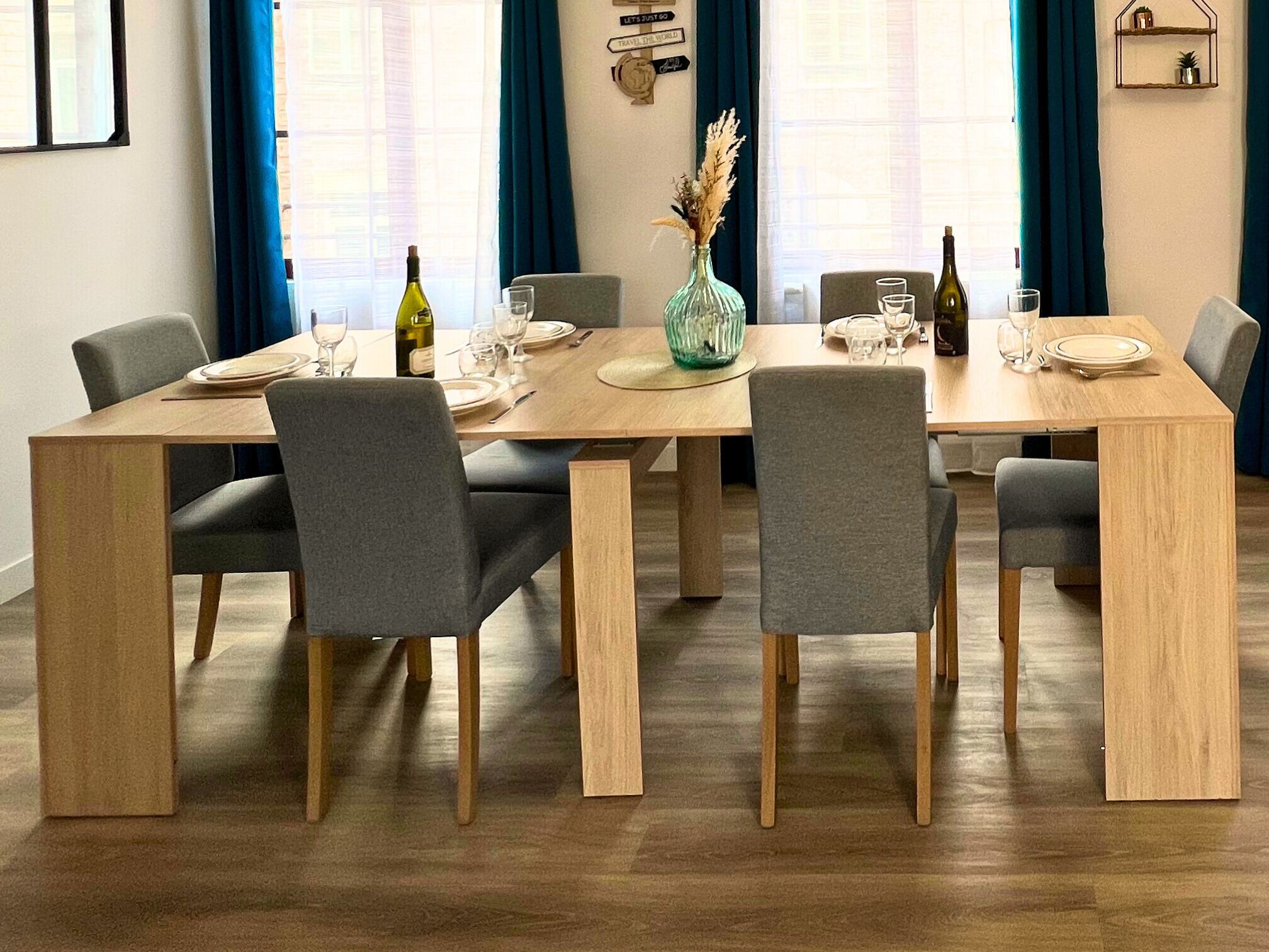 A dining area with a wooden table set for four, surrounded by grey upholstered chairs.