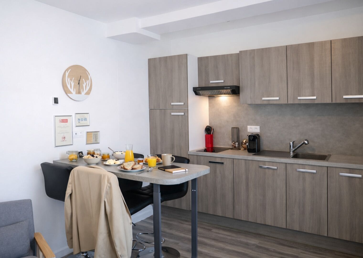 Una cocina moderna con armarios grises, una mesa de comedor con alimentos para el desayuno y una cafetera.