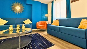 Una sala de estar moderna con un sofá azul, una mesa de centro redonda y un adorno mural con forma de sol.