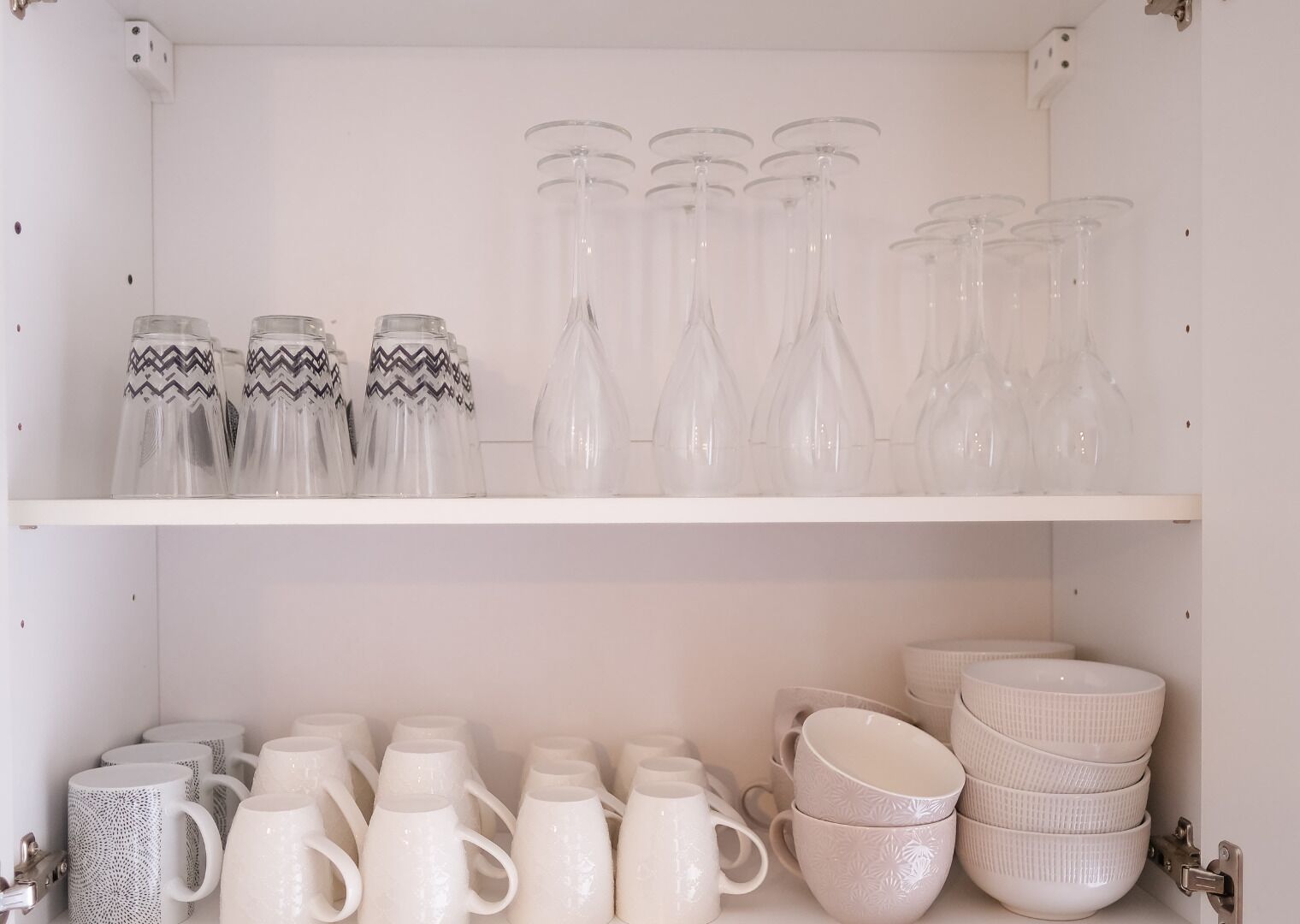 A storage unit with shelves containing various glassware and ceramic mugs.