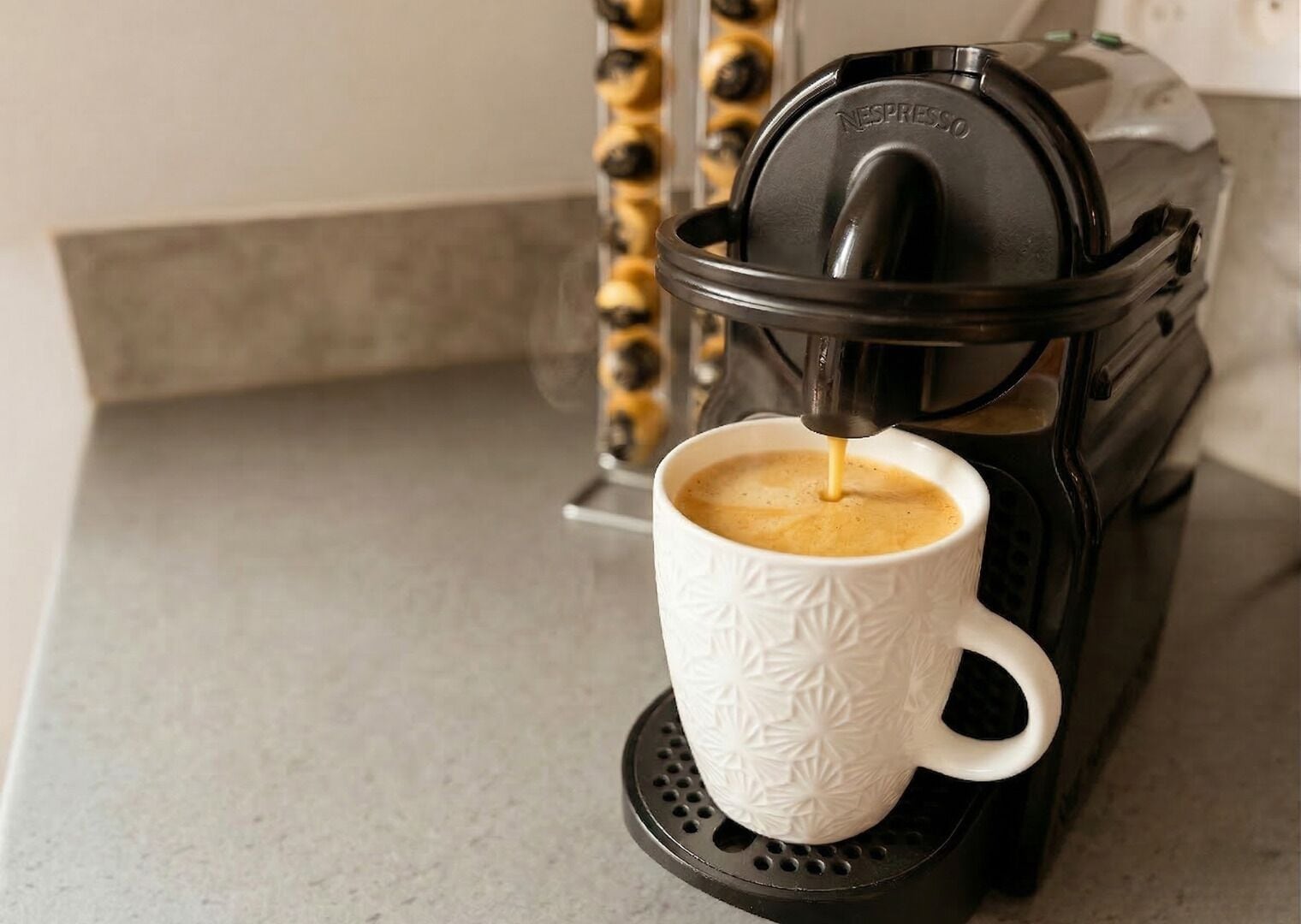 A coffee machine dispensing coffee into a white cup with a textured pattern.