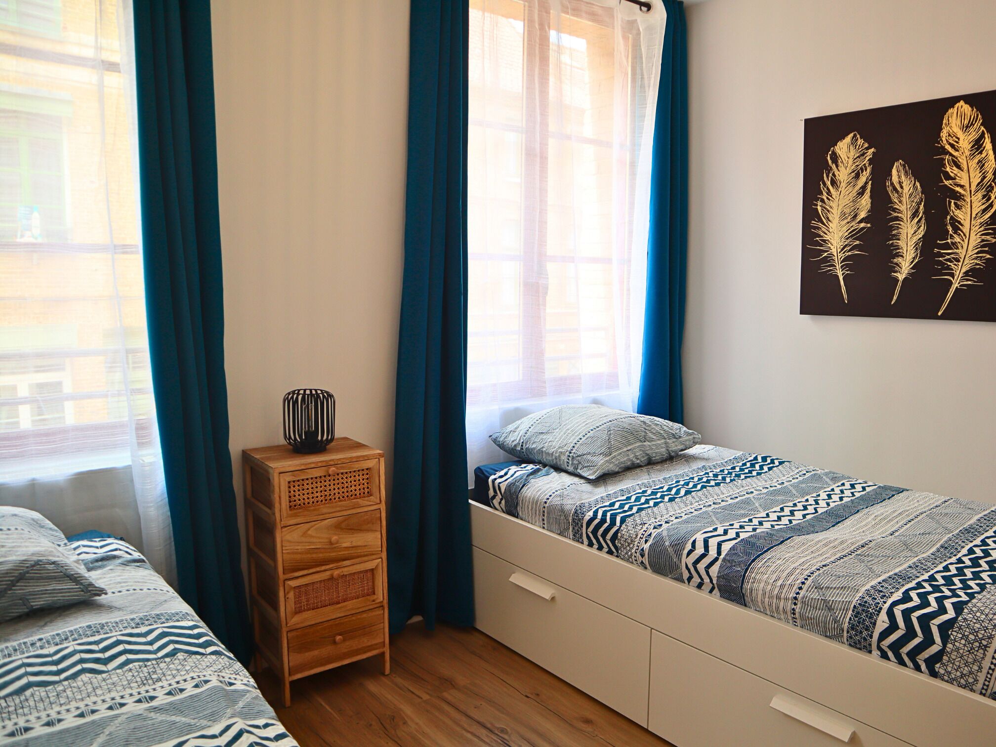A bedroom with two beds, a wooden nightstand, and a wall-mounted artwork.