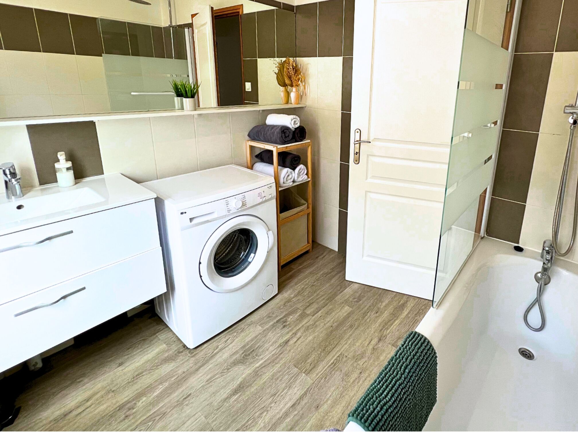 A modern bathroom with a washing machine, a bathtub, and a shower.
