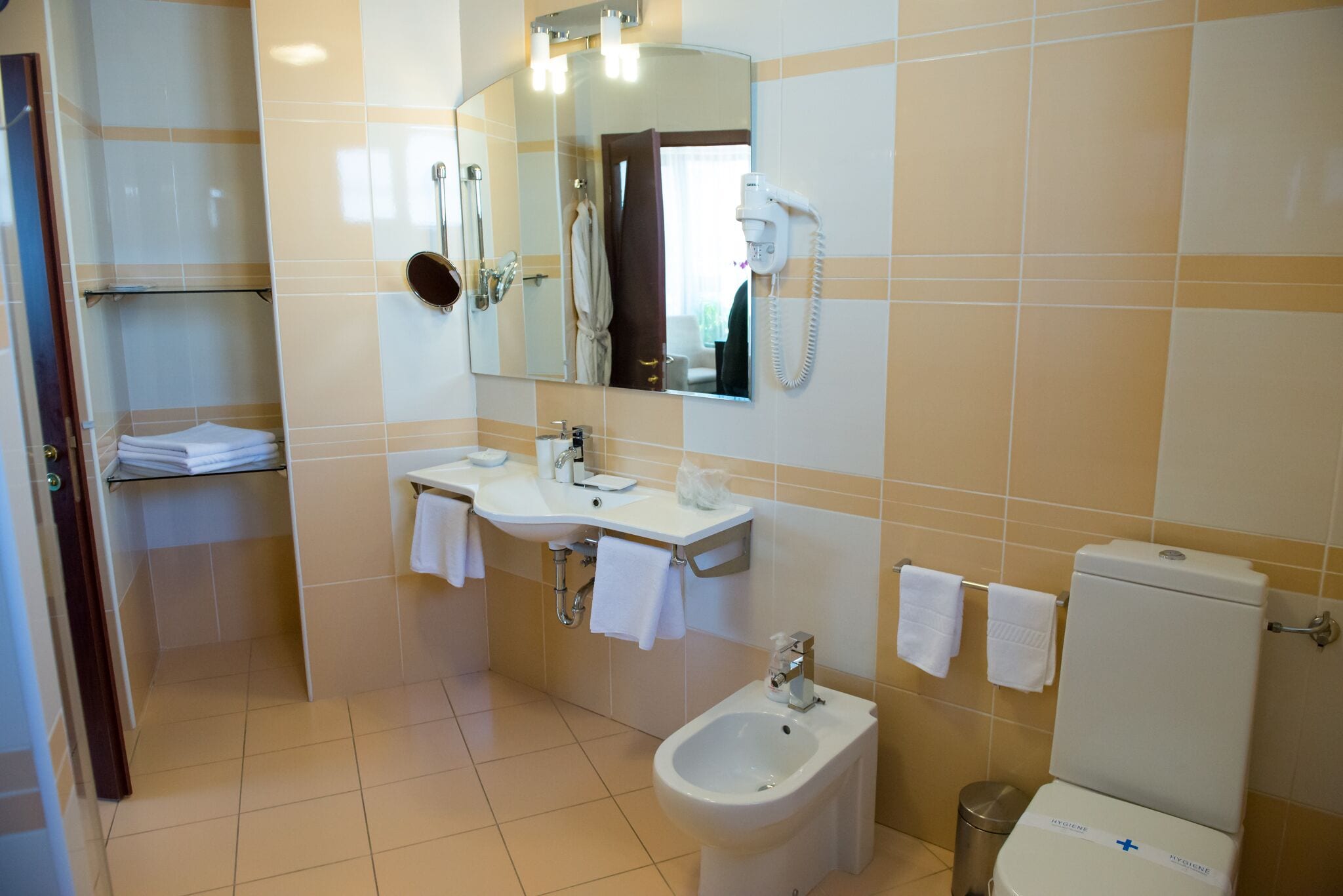 A bathroom with a sink, bidet, toilet, and a mirror.