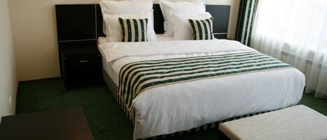 A hotel room with a bed, a bedside table, and a bench.