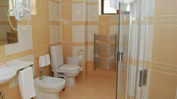A bathroom with a toilet, bidet, and a glass shower enclosure.