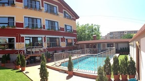A multi-story building with a swimming pool, potted plants, and a well-maintained lawn. - Pensiunea President (Deva)