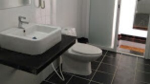 Une salle de bain moderne avec un lavabo blanc, des toilettes et un miroir au-dessus du lavabo.