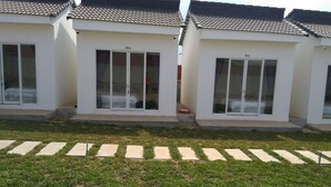Une rangée de bâtiments modernes, blancs, avec des toits en tuiles et de grandes portes-fenêtres coulissantes.