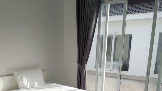 Une chambre d’hôtel avec un lit, une chaise et une vue sur l’extérieur, visible à travers une porte vitrée.