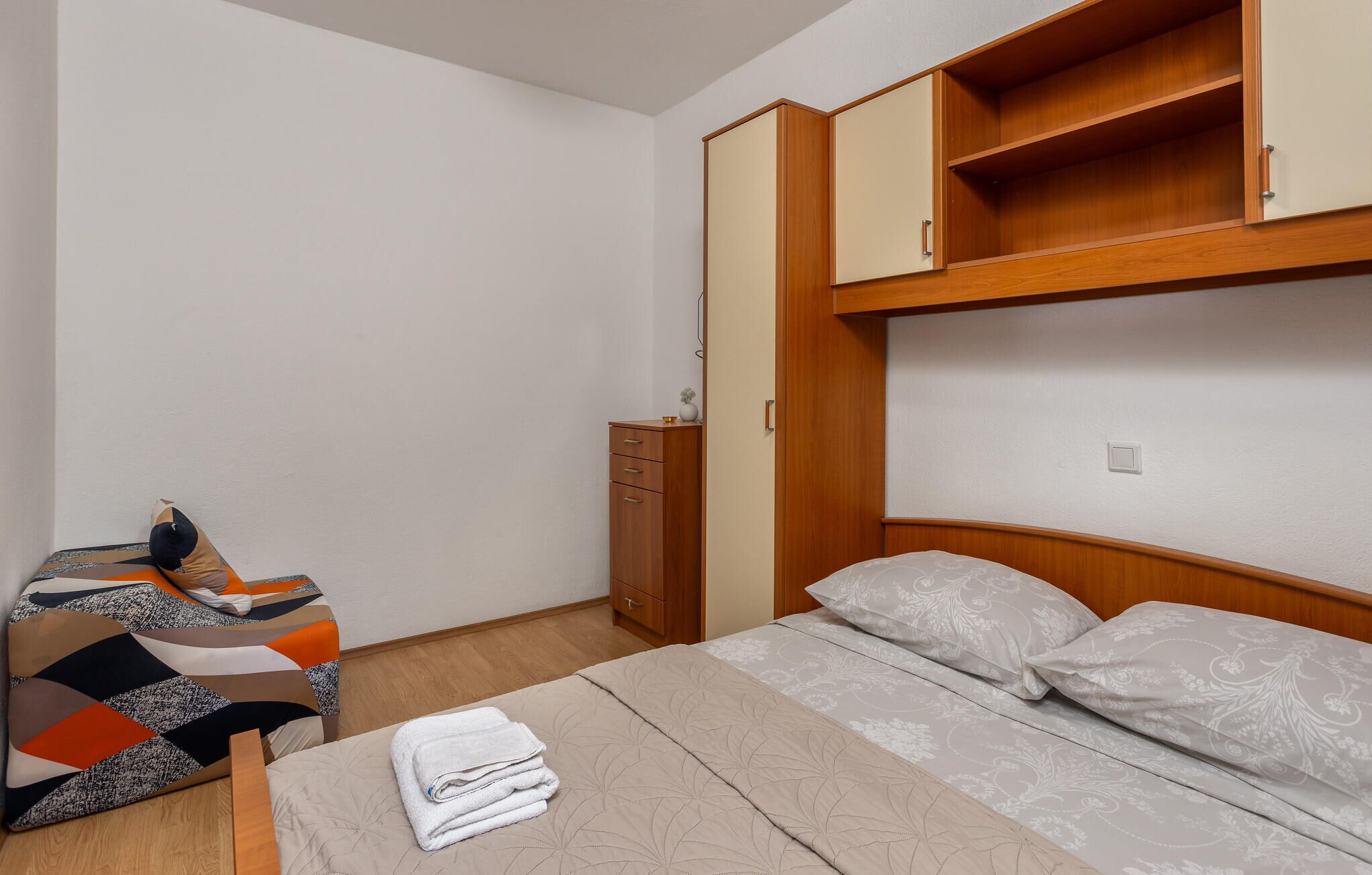A bedroom with a bed, a dresser, and a small table with a chair.