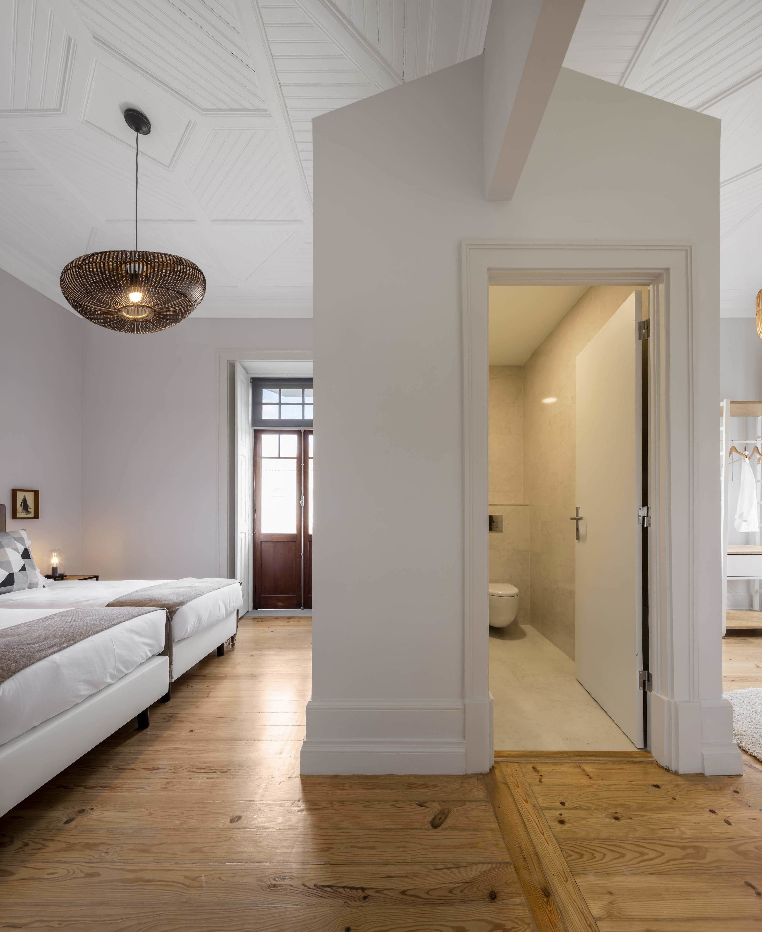 Un dormitorio con una cama grande, una lámpara colgante y vistas al baño.