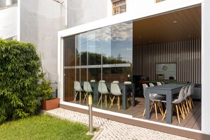 An outdoor dining area with a glass wall, wooden deck, and a potted plant. - Penedo da Saudade Suites & Hostel (Coimbra)