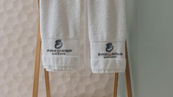 Dos toallas blancas colgadas en un toallero de madera con un logotipo y texto que indican que provienen de un hotel.