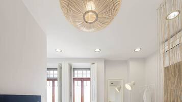 A modern bedroom with a large bed, a hanging light fixture, and a wardrobe.