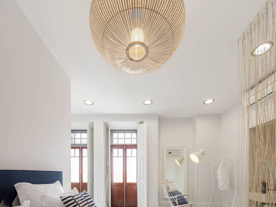A modern bedroom with a large bed, a hanging light fixture, and a wardrobe.