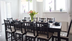 A dining area with a table set for six, surrounded by chairs with cushioned seats. - Bed'n'Work Apartment Prenzlauer Berg (Berlin)