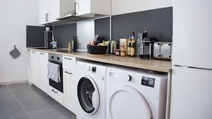 A compact kitchen with a washing machine, a coffee maker, and a toaster. - Bed'n'Work Apartment Prenzlauer Berg (Berlin)