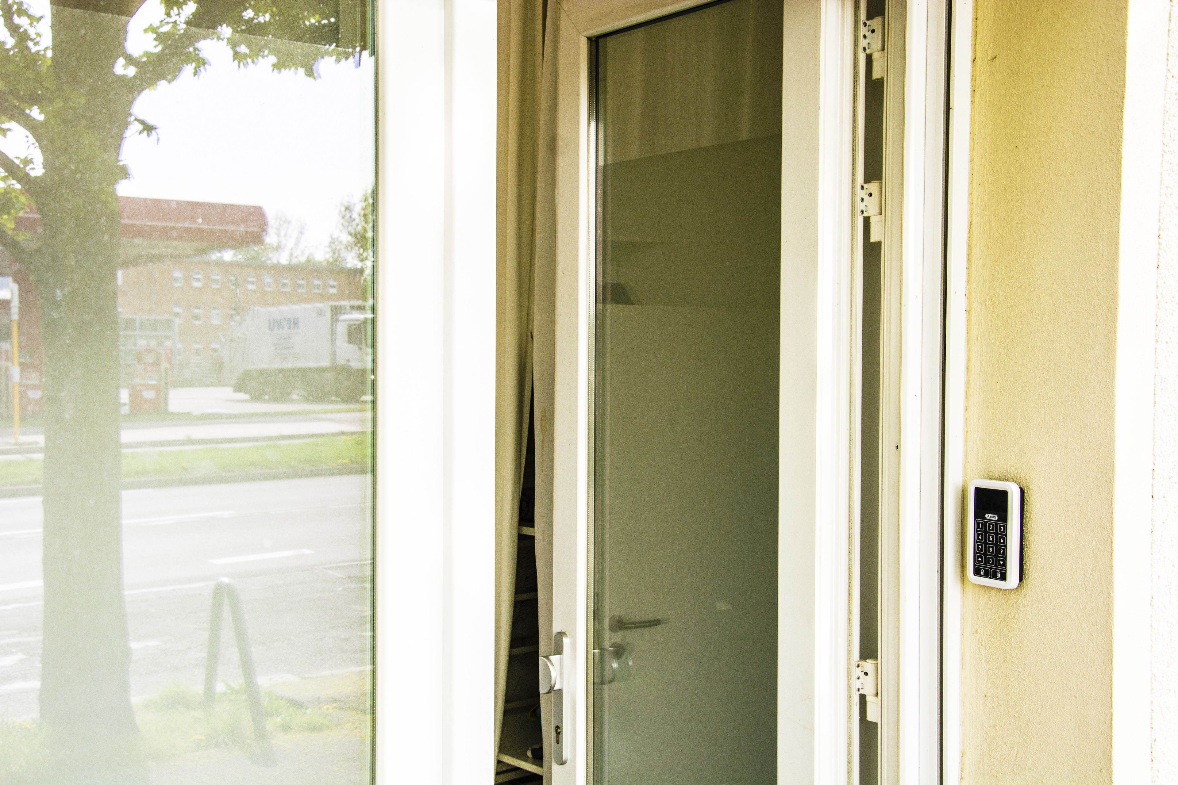 A door with a keypad lock, a glass door, and a view of the street outside.