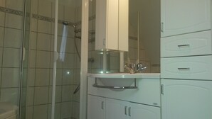 Un bagno con doccia, lavandino e mobiletti.