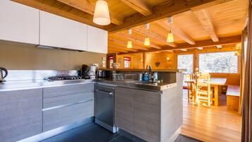 Une cuisine moderne avec des poutres en bois, des appareils électroménagers en acier inoxydable et des luminaires suspendus.