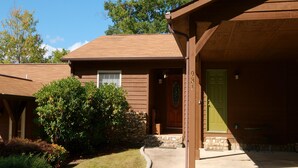 A two-story house with a stone foundation, a green door, and a covered porch.