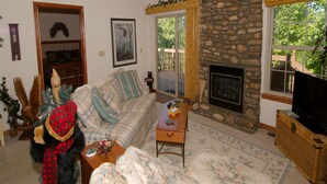A cozy living room with a fireplace, a sofa, a coffee table, and a television.