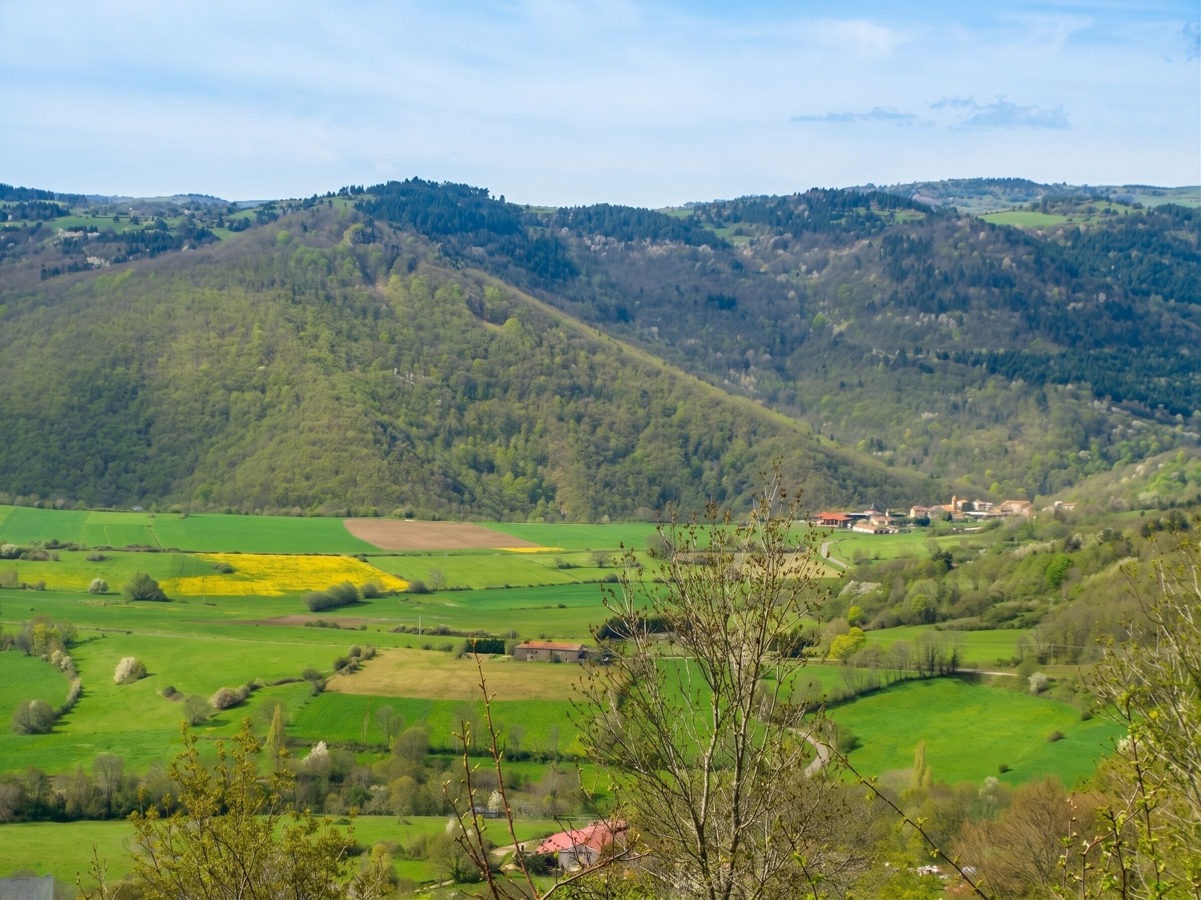 Paisaje rural con colinas onduladas, campos y un pequeño pueblo.