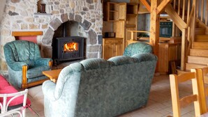 A cozy room with a stone fireplace, wooden furniture, and a staircase.