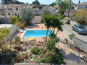 A residential area with a swimming pool, a car, and houses with red-tiled roofs.
