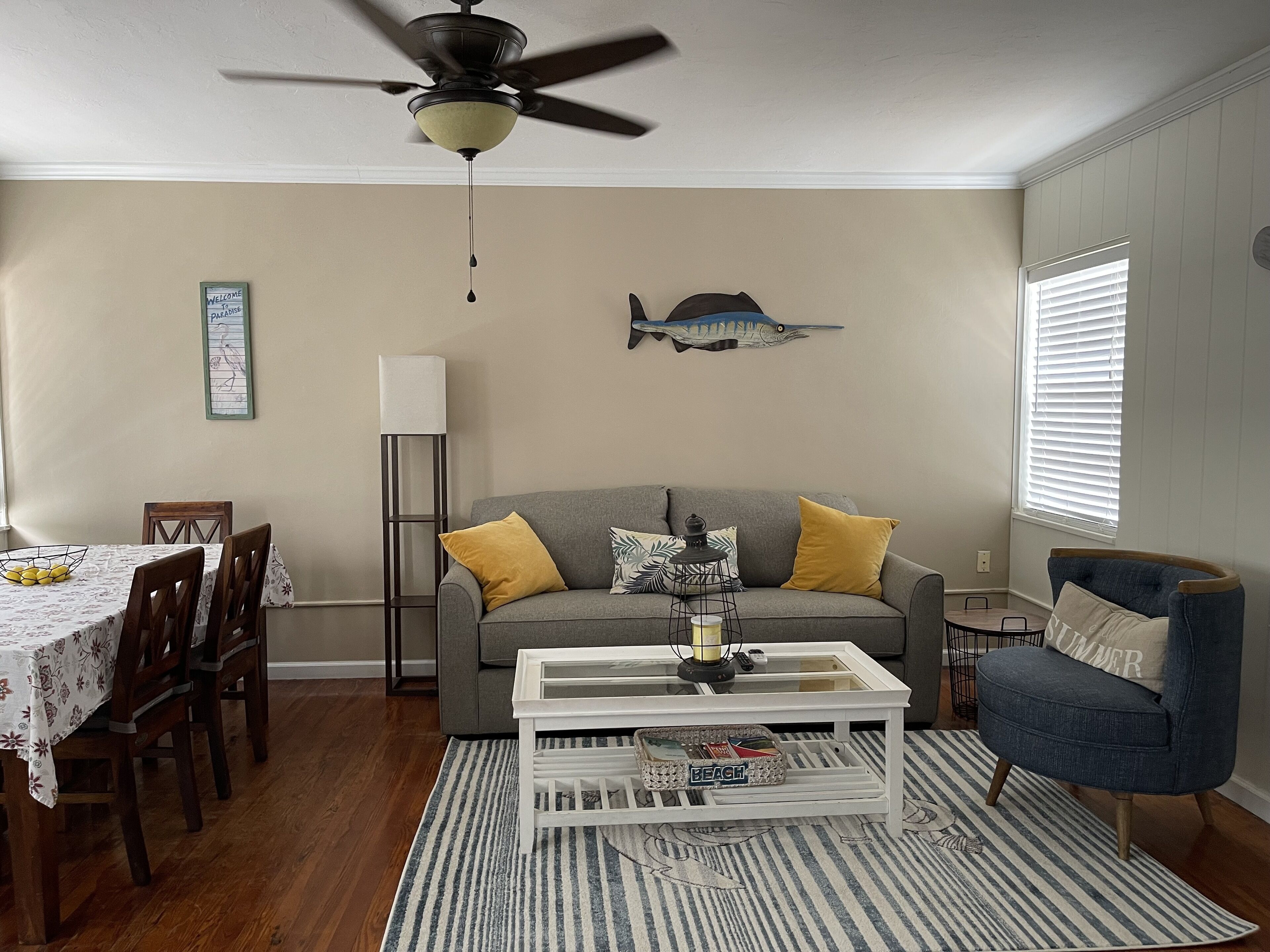 A living room with a gray sofa, yellow cushions, a white coffee table, and a striped rug.