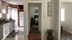Una cocina con armarios blancos, un refrigerador y una estufa. Hay un letrero que dice "BEACH" y otro que dice "SWIM".
